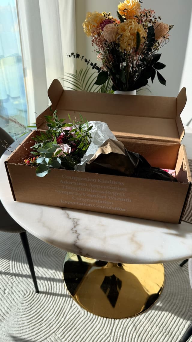 Euroflorists leveranslåda på bordet med buketten i vas bakom